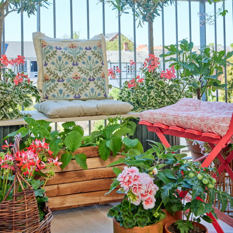 Mały miejski balkon z pelargoniami i roślinami jadalnymi