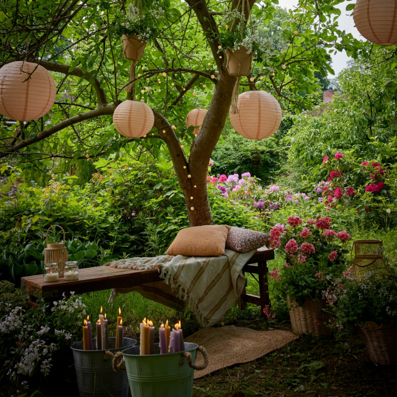 Saloni z pelargoniami i wiszącymi lampionami pod drzewem