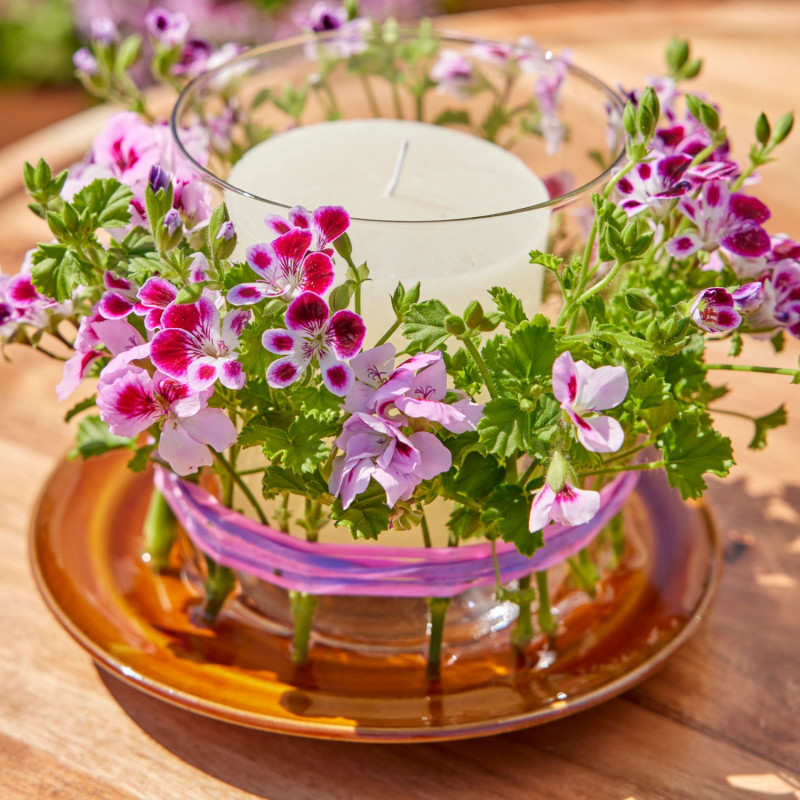Świeca ozdobiona kwiatami pelargonii