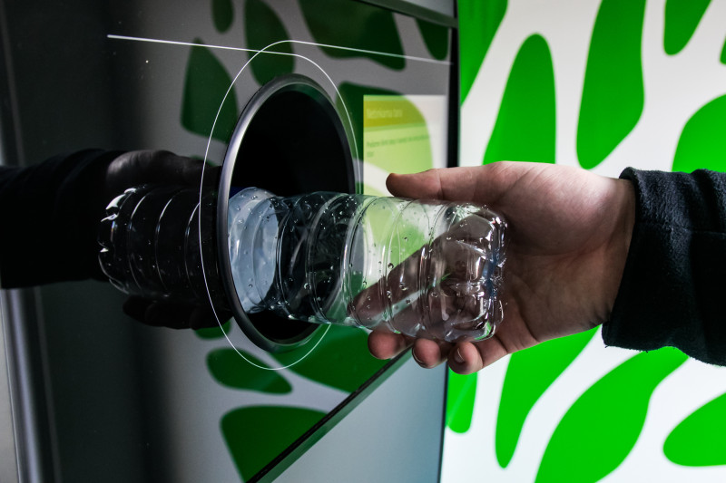 Oddawanie plastikowej butelki do recyklomatu w ramach systemu kaucyjnego w Polsce